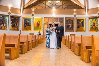 Noiva entrando na igreja vazia, sendo levada pelos pais até o altar. (Foto: Letícia Plein)