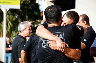 Amigos, policiais civis tentam segurar a tristeza no abraço (Foto: Henrique Kawaminami)