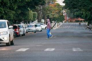 Pedestre atravessa rua usando máscara, que serão distribuídas pelo governo a população vulnerável e profissionais de saúde.