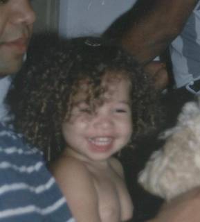 Paola ainda criança toda sorridente e com o cabelinho cacheado. (Foto: Arquivo pessoal)