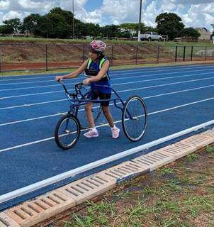 Karen segurando o triciclo na pista e treinando para competições. (Foto: Arquivo pessoal)