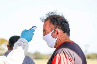 Agente de saúde medindo a temperatura de homem. (Foto: Henrique Kawaminami) 