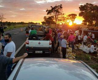 Dezenas de pessoas recolhem caixas de cerveja que estavam em caminhão tombado (Foto: Nova News)