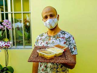 O artista Arce Correia usando máscara de proteção e segurando as marmitas que produz. (Foto: Arquivo pessoal)