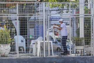 Funcionário recolhe mesas e cadeiras que não podem ser disponibilizadas aos fins de semana. (Foto: Marcos Maluf)
