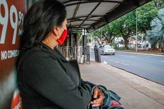 Passageira à espera de ônibus nesta segunda-feira, quando o serviço parou por duas horas em Campo Grande. (Foto: Henrique Kawaminami)