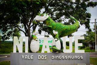 Em Nioaque quem dá as boas vindas aos visitantes é uma fêmea de Abelissauro com seus filhotes, todos de máscaras de proteção contra o coronavírus (Foto: Secretaria de Turismo/Divulgação)