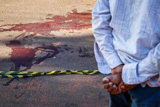 Morador observa marcas de sangue um dia após a rua ser cenário de homicídio. (Foto: Henrique Kawaminami) 