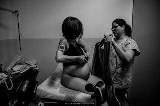 Adriele ainda com a Aurora na barriga, trocando de roupa ao lado da doula Thalita no Hospital Universitário. (Foto: Paula Cayres)