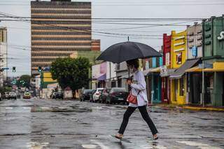 Pedestre atravessando rua do Centro de Campo Grande, na manhã desta quinta-feira, em dia chuvoso e frio (Foto: Marcos Maluf)