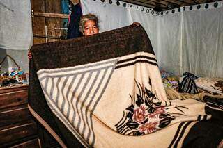 Maria Aparecida dos Santos Silva, 60 anos, mostrando a única coberta grossa que tem em casa. (Foto: Henrique Kawaminami)