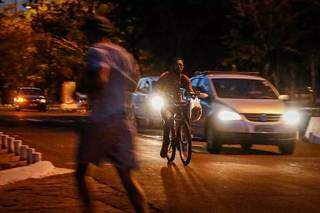 Homem correndo, clista passando e carros circulando por trecho do Parque dos Poderes, no período da noite (Foto: Henrique Kawaminami)