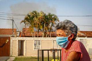 Cleidemar Silvino Correia, 64 anos, moradora de rua lateral do mercado, relata terror durante a noite; nos fundos, ainda é possível ver a fumaça (Foto: Henrique Kawaminami)