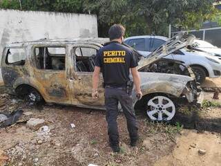 Perito da Polícia Civil observa veículo destruído pelo fogo e levado para pátio de delegacia (Foto: Adilson Domingos)