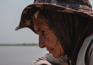 Mulher no Pantanal olhando peixe agonizar pela falta de oxigênio. (Foto: Nathalia do Valle / Comitiva Esperança)