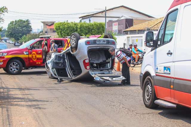 Padre desvia de ciclista, bate em carro parado e capota Fiat Uno 