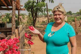 Em um barraco vizinho, Reinalda mostra uma das flores que cultivou (Foto: Silas Lima)