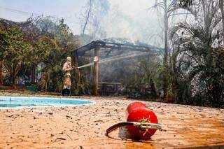 Bombeiro combate incêndio que atingiu estrutura do chalé (Foto: Henrique Kawaminami)