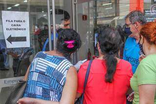 Funcionário controlando a entrada e explicando aos clientes sobre as filas. (Foto: Marcos Maluf)