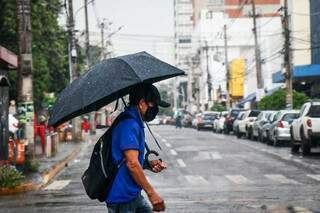 Homem se protege com guarda-chuva no Centro da Capital (Foto: Henrique Kawaminami)