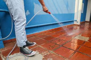 Rapaz utiliza água para limpar quintal de residência (Foto: Paulo Francis)