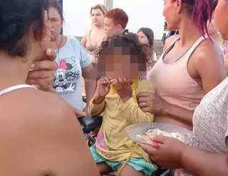 Criança sendo alimentada por moradores após ser encontrada no bairro. (Foto: Direto das Ruas)