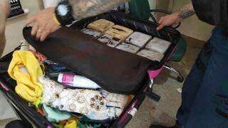 Policial retira tabletes de maconha de mala encontrada com modelo de 17 anos (Foto: Adilson Domingos)