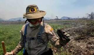 Militar segurando pedaço do solo, cujo interior fora atingido pelas chamas (Foto: Reprodução)