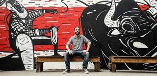 Pedro Morato ao lado de grafite feito por ele em uma hamburgueria. (Foto: Arquivo Pessoal)