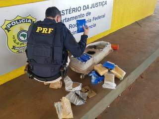 Policial retirando os tabletes da droga de dentro do tanque do veículo. (Foto: PRF)