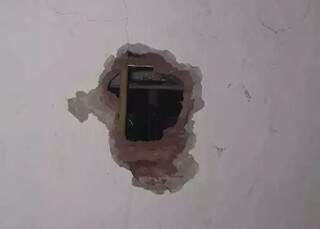 Buraco que foi feito pelo assaltante na parede dos fundos do imóvel. (Foto: Divulgação/PM) 