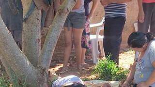 Mulher ajoelhada ao lado de corpo, hoje em Ponta Porã (Foto: Direto das Ruas)