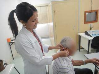 Fonoaudióloga da UCDB realiza a entrega do aparelho auditivo gratuito a paciente (Foto: Divulgação)