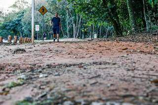 Pedestre cmainha sobre calçada danificada no Parque dos Poderes, em Campo Grande. (Foto: Henrique Kawaminami)
