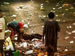 Homem é socorrido por amigo em meio a lixo, em dia de carnaval (Foto: Marcos Maluf / Arquivo)