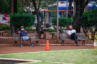 Pessoas sentadas na praça Ary Coelho, no Centro de Campo Grande (Foto: Henrique Kawaminami)
