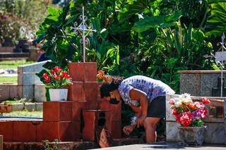Mulher visitando túmulo de parente em cemitério da Capital. (Foto: Henrique Kawaminami)