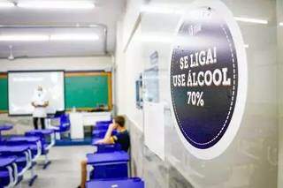 Placa alerta para a necessidade de uso de álcool 70% pelos alunos na precaução à covid-19. (Foto: Arquivo/Campo Grande News)