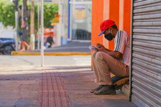 Rapaz faz anotações no Centro da Capital e mesmo sem ninguém por perto mantém a máscara no rosto (Foto: Marcos Maluf/Arquivo)