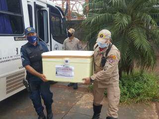 Bombeiro e policial militar carregam caixa térmica com doses da vacina (Foto: Divulgação)