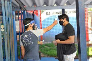 Aferição de temperatura dos candidatos às vagas da UFGD é feita no portão de entrada da Escola Joaquim Murtinho, em Campo Grande (Foto: Paulo Francis)