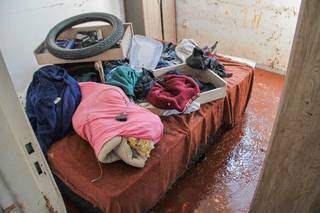 Roupas, pneu e lençol sobre a cama que está dentro do quarto sujo de lama. (Foto: Marcos Maluf)