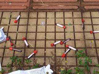 Frascos de coletas de sangue jogados de forma irregular em via pública. (Foto:Direto das Ruas)
