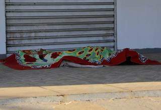 O corpo de Carla, abandonado em calçada de comércio vizinho à familia, coberto por manta levada pela família. (Foto: Kísie Ainoã)
