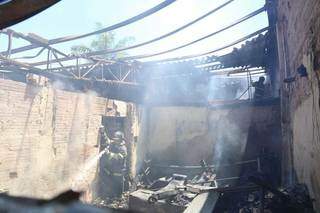 Bombeiro jogando água para conter incêndio dentro da loja de MDF que foi destruida pelas chamas. (Foto: Paulo Francis)