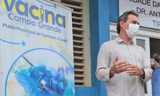 Marquinhos Trad ao lado de cartaz sobre a vacina da covid-19, que ele defende como eficaz. (Foto: Divulgação)