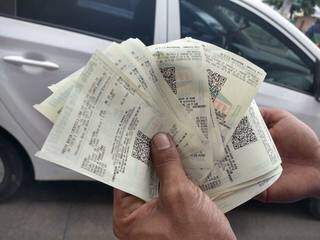 Motorista segurando as notas fiscais impressas após o abastecimento de alguns dos carros. (Foto: Mariana Rodrigues)