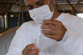Profissional de saúde insere dose de vacina na seringa (Foto: Kisie Ainoã)