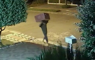 Imagem mostra o momento em que o ladrão foge levando uma caixa cheia de roupas (Foto: reprodução / vídeo) 
