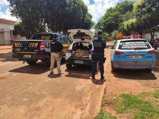 Policiais ao lado do veículo onde foram encontrados os tabletes de drogas. (Foto: PRF)